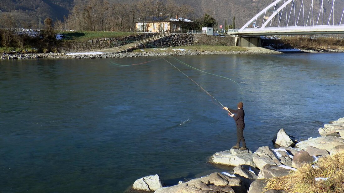 Istruttore di lancio che corregge l'allievo in riva al fiume